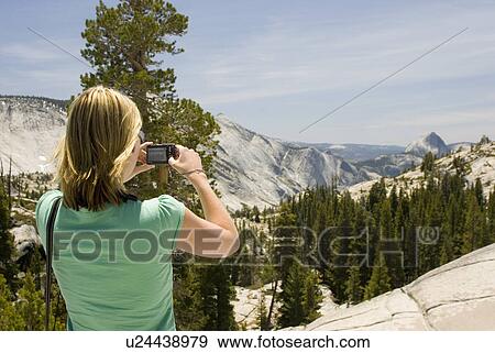 Stock Photo - Woman taking picture of mountains. Fotosearch