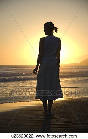 Stock Image - Young female on the beach at sunset. Fotosearch