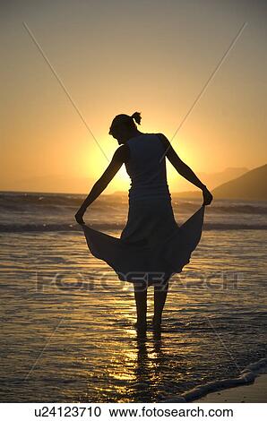 Stock Image - Young female on the beach at sunset. Fotosearch
