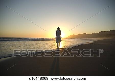 Stock Photo - Young female on the beach at sunset. Fotosearch
