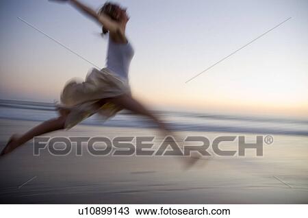 Young female on the beach jumping at sunset View Large Photo Image Stock Image - Young female on the beach jumping at sunset. Fotosearch