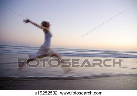 Young female on the beach jumping at sunset View Large Photo Image Stock Image - Young female on the beach jumping at sunset. Fotosearch