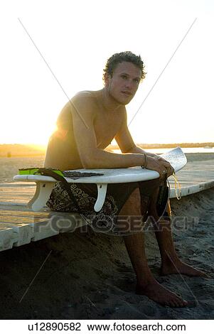 Young male surfer holding surfboard View Large Photo Image Stock Image - Young male surfer holding surfboard. Fotosearch