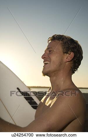 Stock Image - Young male surfer laughing. Fotosearch