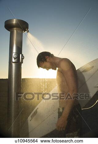 Picture - Young male surfer rinsing off in the shower. Fotosearch