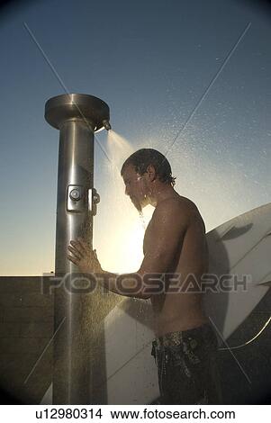Picture - Young male surfer rinsing off in the shower. Fotosearch