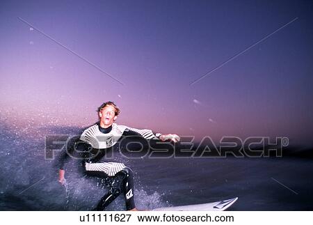 Young surfer doing a bottom turn just after sunset View Large Photo Image Stock Photo - Young surfer doing a bottom turn just after sunset. Fotosearch
