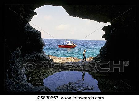 Boat on the ocean seen through opening in rock structure View Large Photo Image Stock Photo - Boat on the ocean seen through opening in rock structure. Fotosearch