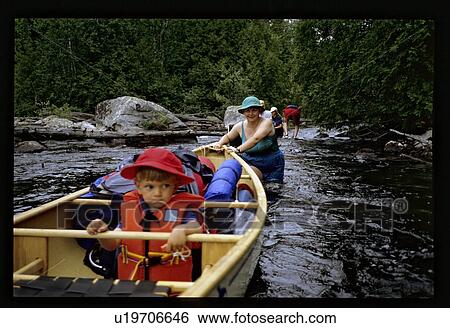 Stock Photograph - Boy in a canoe with mom pushing. Fotosearch