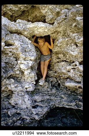 Picture - Boy in a rock cave. Fotosearch