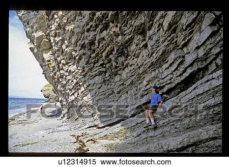 Stock Photography - Boy sitting on a rock shoreline . Fotosearch