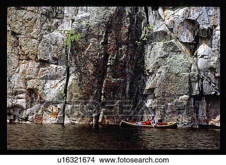 Picture - Canoe beside rock cliff. Fotosearch