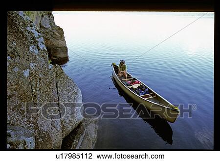 Stock Image - Canoeing next to a rock wall. Fotosearch