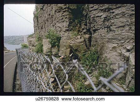 Stock Photo - Chain-link fence holding back rocks . Fotosearch