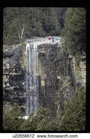 Couple standing next to a waterfall View Large Photo Image Stock Image - Couple standing next to a waterfall. Fotosearch