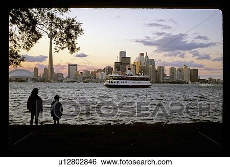 Stock Photograph - Ferry in front of a city. Fotosearch