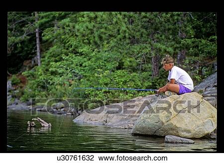Stock Image - Fishing on a rock. Fotosearch