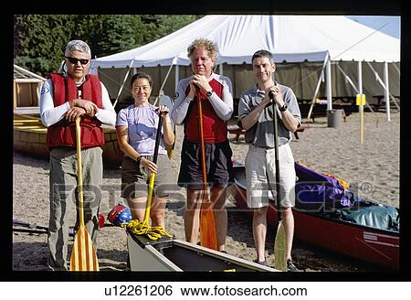 Stock Photograph - Four people holding canoe paddles. Fotosearch