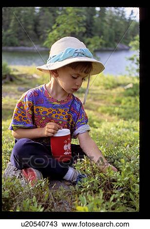 Stock Image - Girl sitting in the grass by a lake. Fotosearch