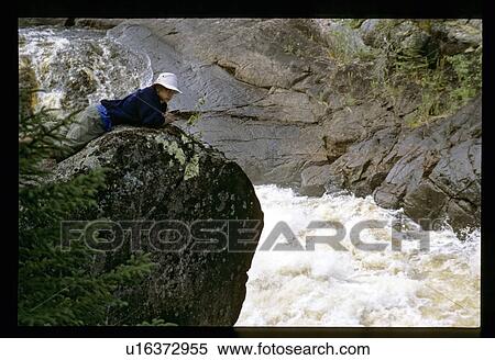 Stock Photography - Laying on a rock over whitewater. Fotosearch