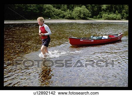 Man pulling canoe in water View Large Photo Image Stock Image - Man pulling canoe in water. Fotosearch