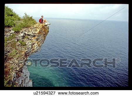 Man sitting on a ledge high above the water View Large Photo Image Stock Photo - Man sitting on a ledge high above the water. Fotosearch