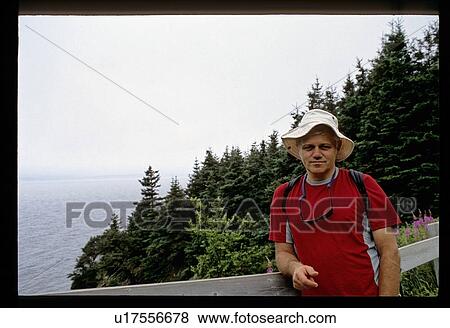 Stock Photo - Man standing by a fence . Fotosearch