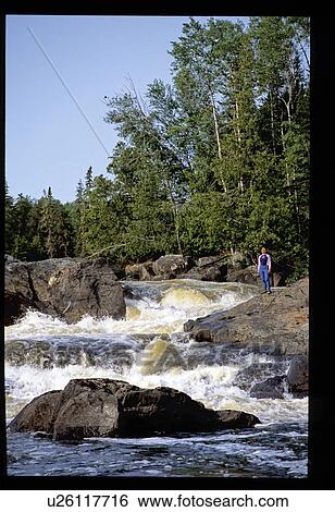 Stock Photograph - Person on rock by river. Fotosearch
