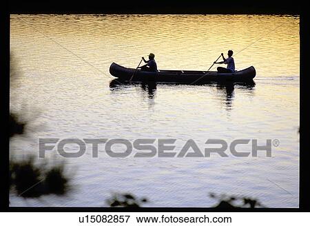 Silhouette of two people canoeing on a lake View Large Photo Image Stock Photo - Silhouette of two people canoeing on a lake. Fotosearch