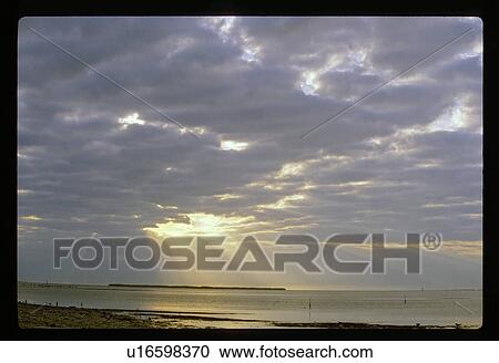 Sun coming through clouds over a lake View Large Photo Image Stock Image - Sun coming through clouds over a lake. Fotosearch