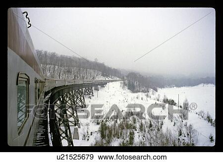 Stock Photo - Train on a snowy mountain bridge. Fotosearch