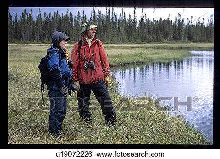 Stock Photograph - Two hikers looking at lake. Fotosearch