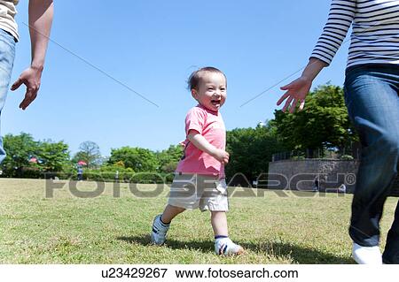 Stock Photo - Baby Boy Walking in Park with Parents. Fotosearch