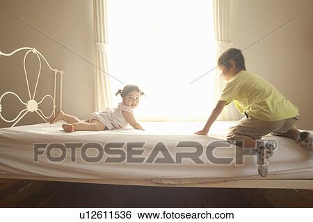 Stock Photograph - Baby Girl and Boy Playing on Bed. Fotosearch