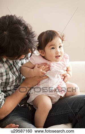 Stock Image - Baby Girl Sitting on Father's Lap. Fotosearch