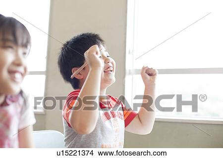 Picture - Boy Celebrating Success in Classroom. Fotosearch