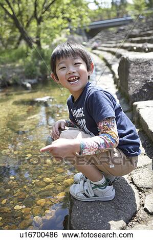 Stock Photograph - Boy Crouching by Pond. Fotosearch