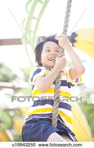 Stock Image - Boy Swining on Rope. Fotosearch