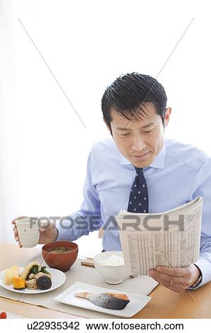 Stock Image - Businessman Having Breaksfast and Reading Newspaper. Fotosearch