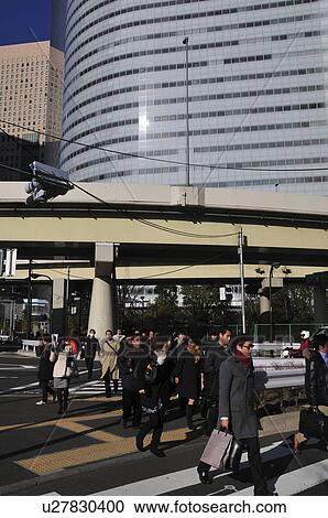 Stock Image - Commuter crossing street, Shiodome, Chuo Ward, Tokyo Prefecture, Honshu, Japan. Fotosearch