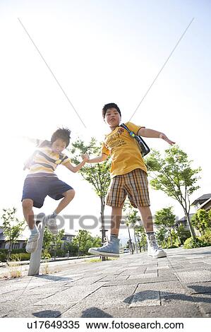 Stock Photography - Elementary school boys jumping, low angle view, Japan. Fotosearch