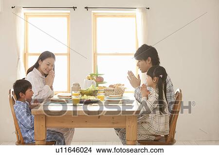 Picture - Family Of Four Praying at Breakfast Table. Fotosearch