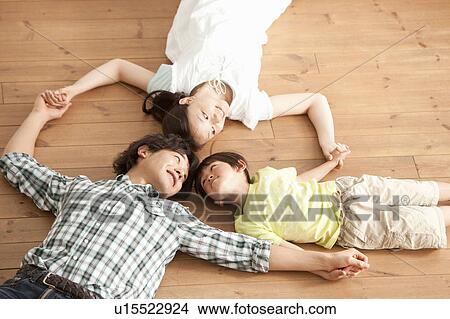 Family of Three Lying on Floor and Holding Hands View Large Photo Image Picture - Family of Three Lying on Floor and Holding Hands. Fotosearch