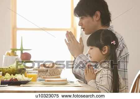 Stock Photography - Father and Daughter Praying at Breakfast Table. Fotosearch