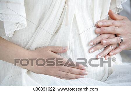 Stock Image - Hands on Pregnant Woman's Stomach. Fotosearch