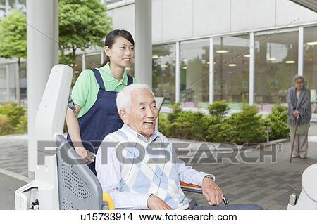 Healthcare worker helping senior man in wheelchair getting into a van, Kanagawa Prefecture, Honshu, Japan View Large Photo Image Picture - Healthcare worker helping senior man in wheelchair getting into a van, Kanagawa Prefecture, Honshu, Japan. Fotosearch