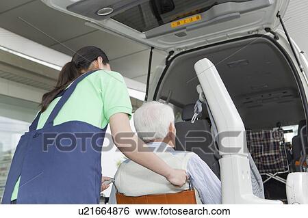 Stock Photograph - Healthcare worker helping senior man in wheelchair getting into a van, Kanagawa Prefecture, Honshu, Japan. Fotosearch