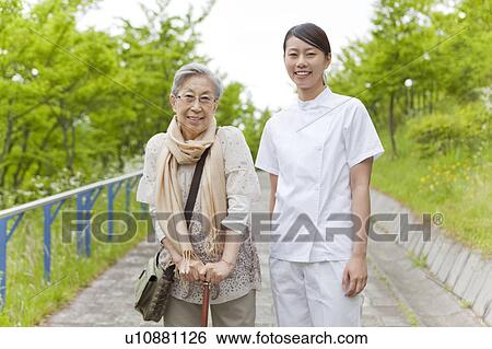 Stock Photograph - Healthcare worker with senior woman, Kanagawa Prefecture, Honshu, Japan. Fotosearch