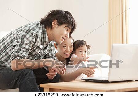 Stock Image - Mother, Father and Baby Girl Using Laptop. Fotosearch