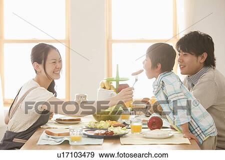 Mother Offering Sausage to Son, Father Watching View Large Photo Image Stock Photo - Mother Offering Sausage to Son, Father Watching. Fotosearch